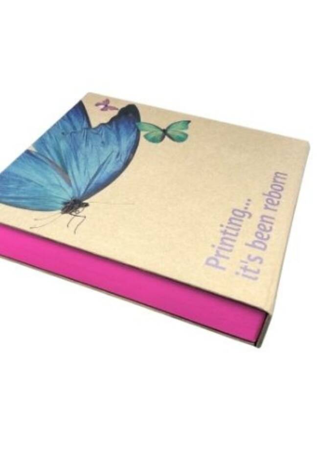 A notebook with a craft paper cover featuring a blue butterfly illustration and the text "Printing... it's been reborn." The spine of the notebook is bright pink.