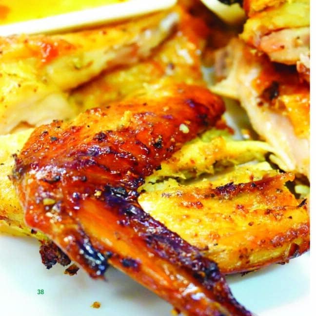 Close-up of roasted chicken pieces with crispy golden-brown skin on a white plate.